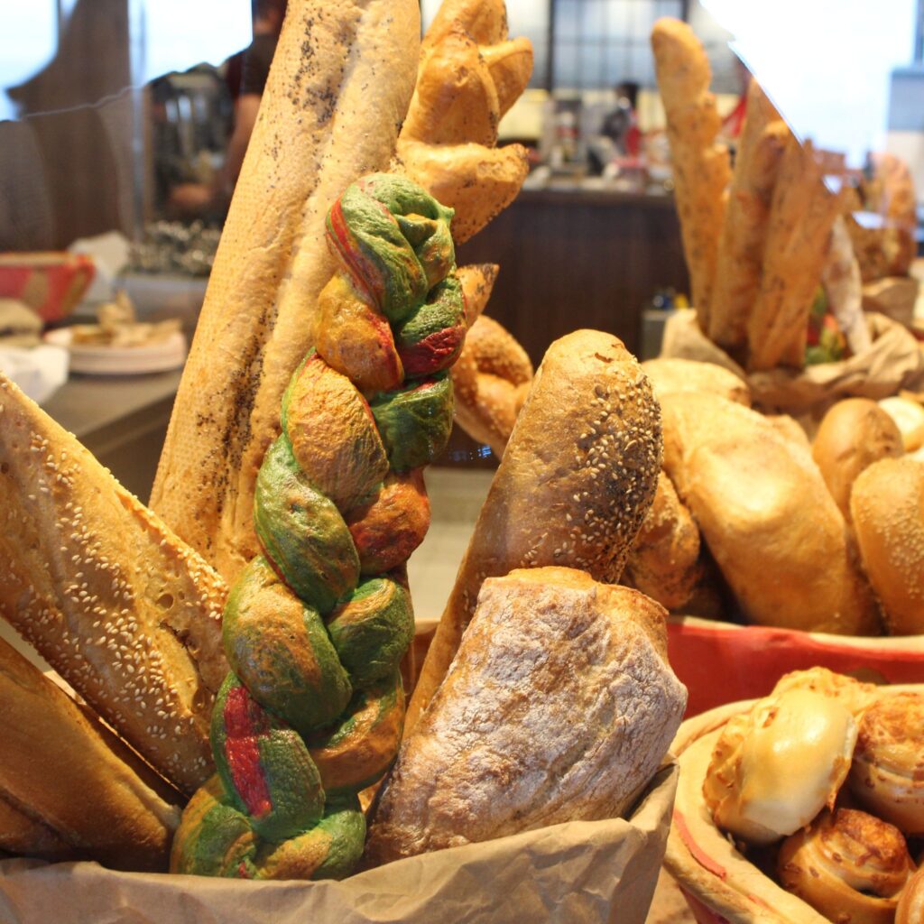 A variety of breads, including long loaves and braided bread, displayed on a buffet line.

