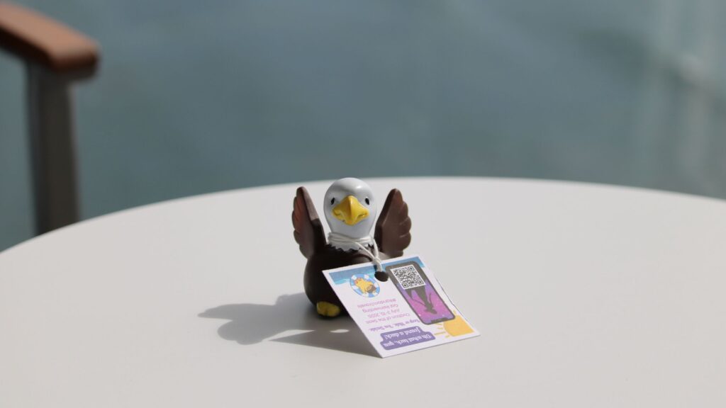 A small rubber eagle figurine, sitting on a table with a tag attached to it.