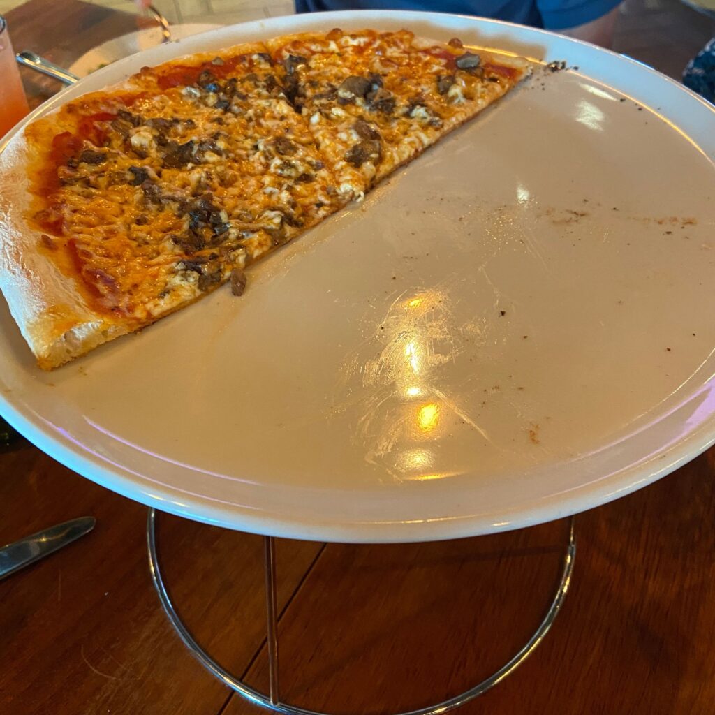 A half-eaten mushroom pizza on a round tray.