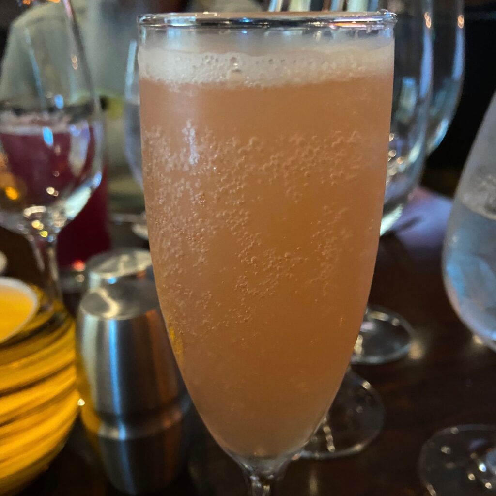 Up close of a flute of a sparkling liquid on a table.